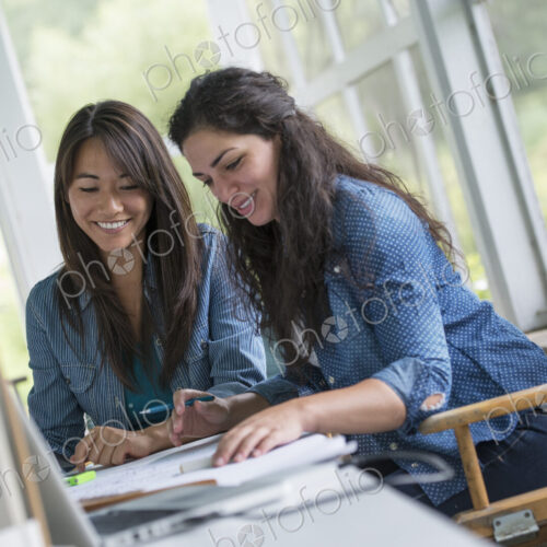 Two women working together, looking at the screen of a digital tablet.