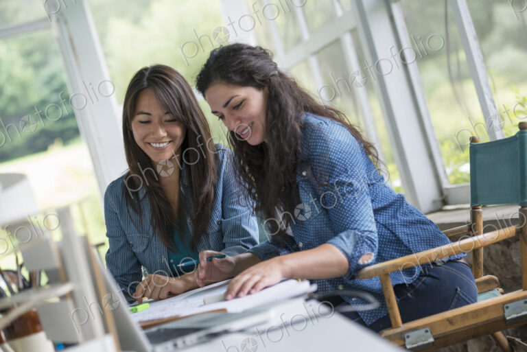 Two women working together, looking at the screen of a digital tablet.
