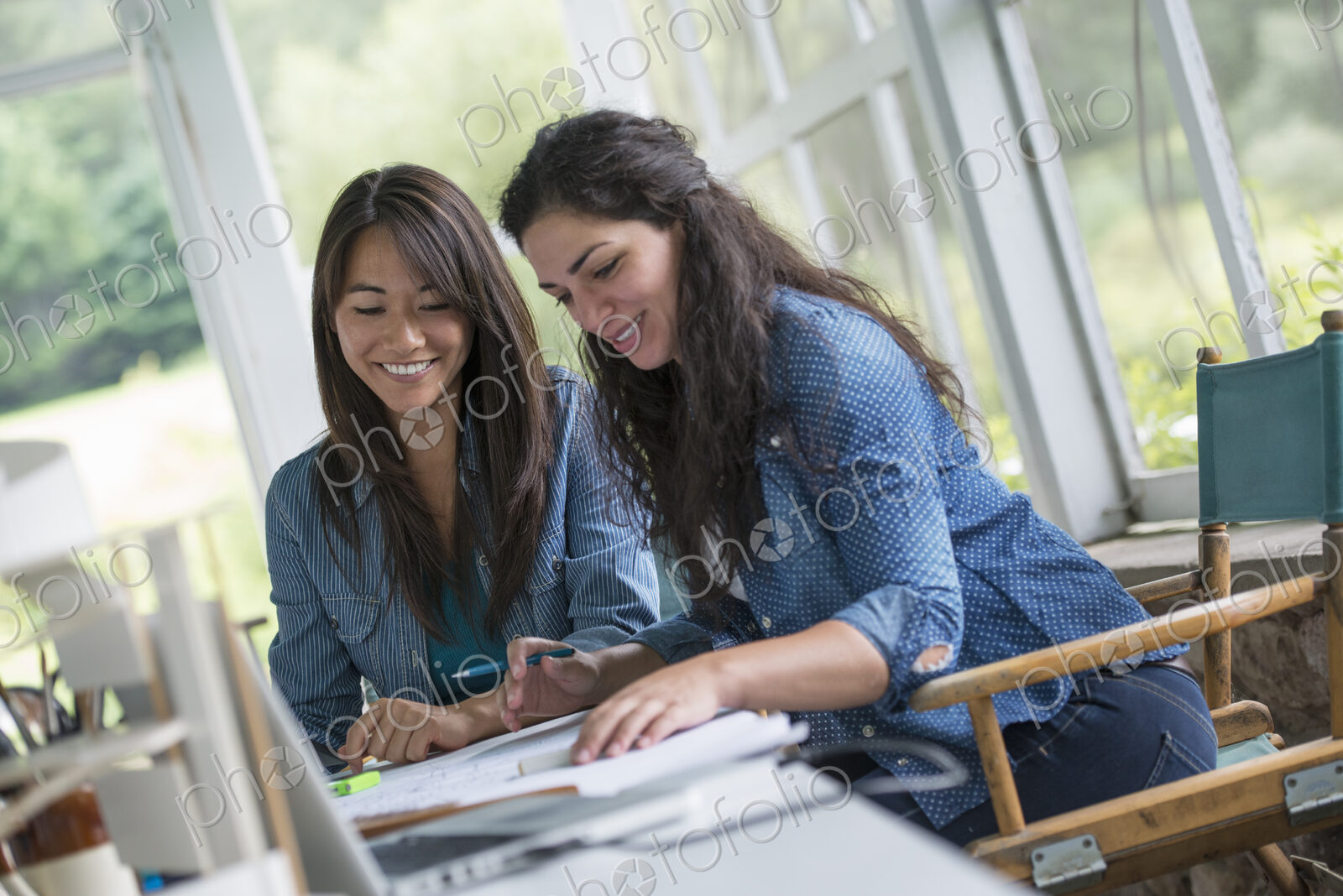 Two women working together, looking at the screen of a digital tablet.