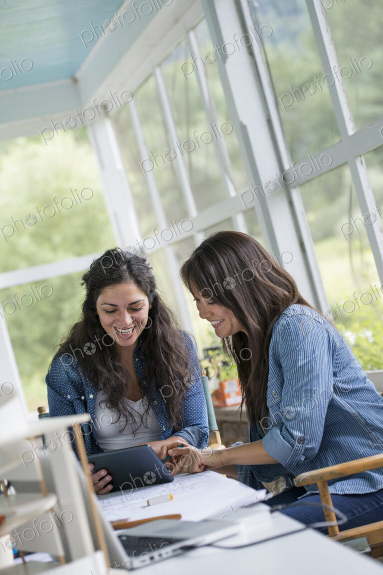 Two women working together, looking at the screen of a digital tablet.