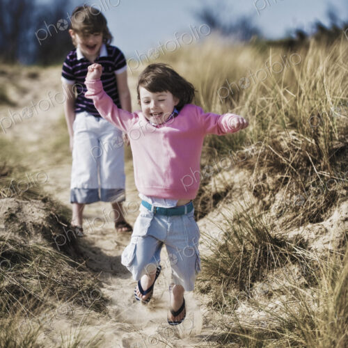 Two young children playing in the dunes.