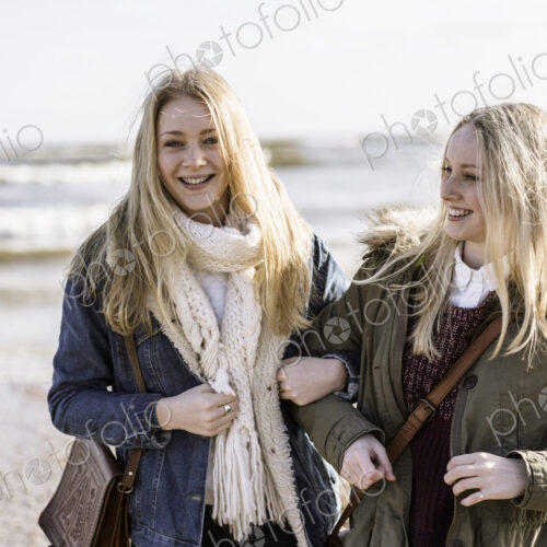 Two young girls on a beach in winter. Two young girls on a beach in winter.