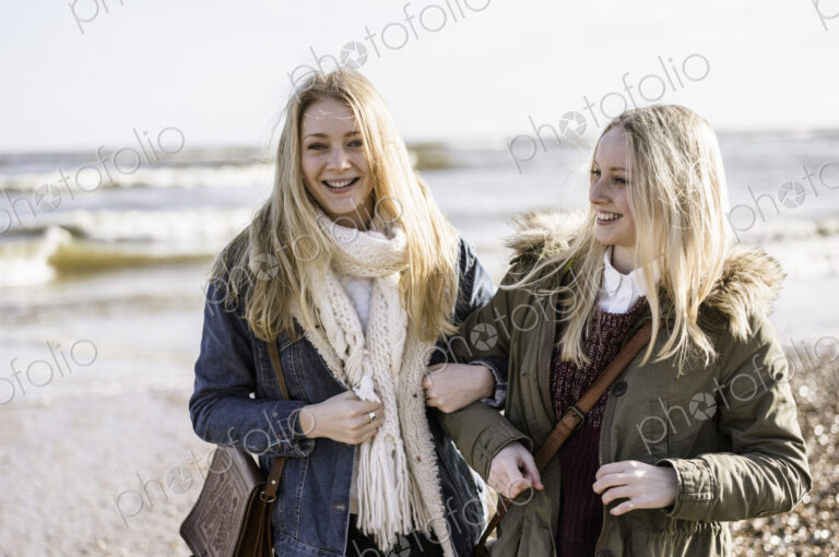 Two young girls on a beach in winter.