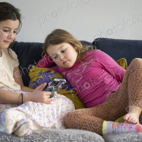 Two young girls sitting on sofa looking at smart phone. Two young girls sitting on sofa looking at smart phone.