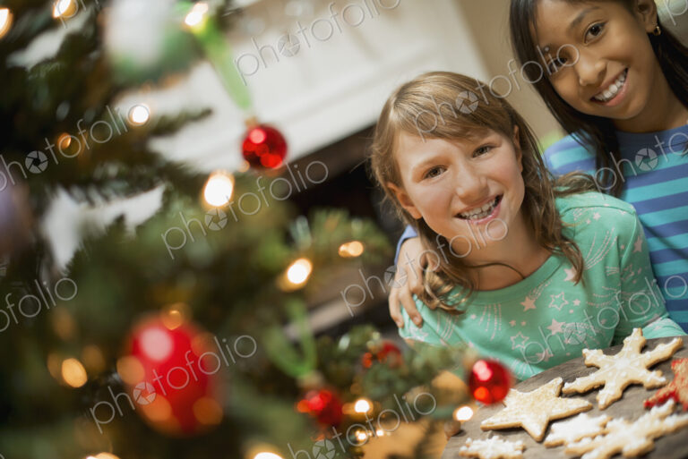 Two young girls with a tray of organic baked and iced Christmas cookies.