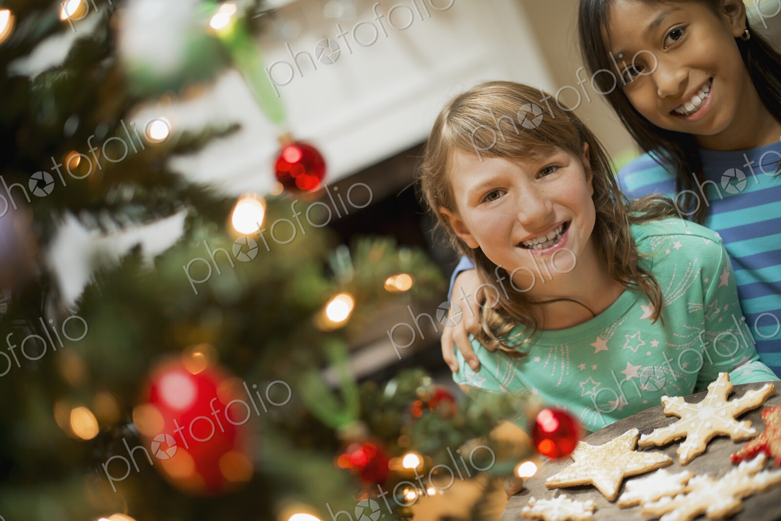 Two young girls with a tray of organic baked and iced Christmas cookies.