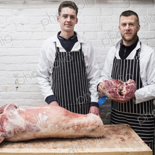 Two young men working, butchers jointing a whole lamb carcass. Two young men working, butchers jointing a whole lamb carcass.