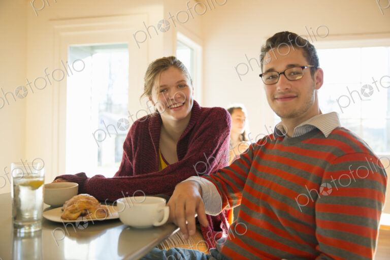 Two young people, a man and a young woman sitting at a counter in a coffee shop.