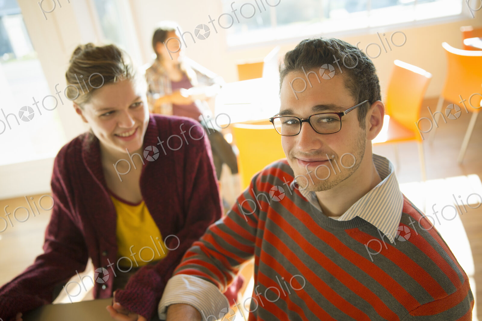 Two young people, a man and a young woman sitting at a counter in a coffee shop.