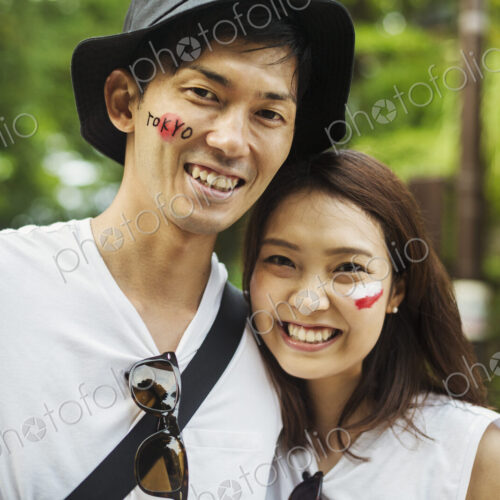 Two young people in woodland, with Japanese flags painted on their cheeks