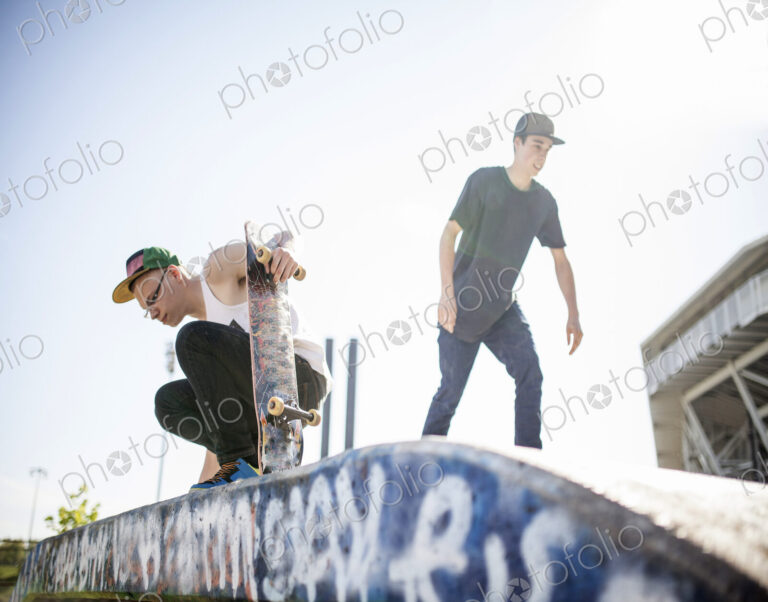 Two young people skateboarding, at a skate park.