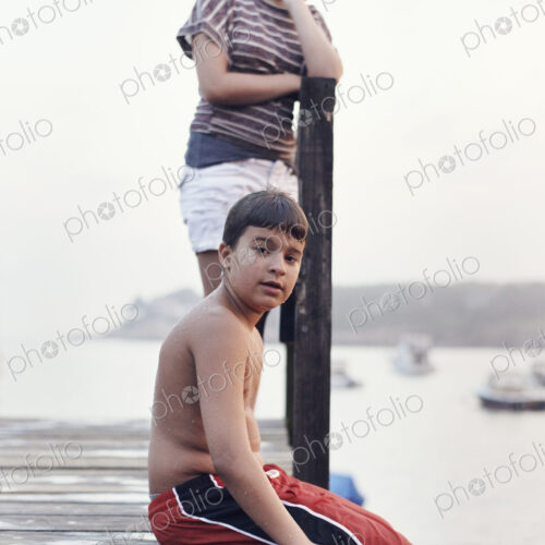 Two young people, teenagers, boy and girl, on a dock overlooking moored boats on the… Two young people, teenagers, boy and girl, on a dock overlooking moored boats on the…