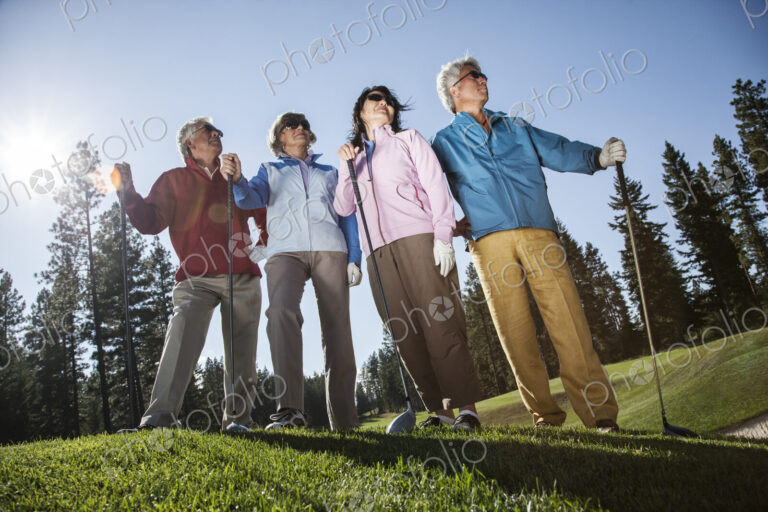 Two young senior golfing couples on the course and ready to play.