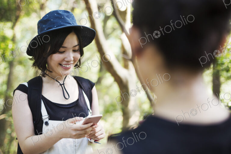 Two young women standing in a forest.