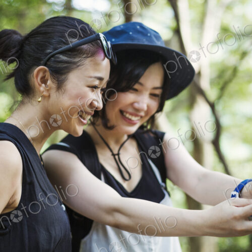 Two young women standing in a forest, taking a selfie.