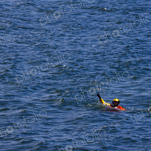 US Coast Guard helicopter demo rescue with rescue swimmer in the water with a raised hand. US Coast Guard helicopter demo rescue with rescue swimmer in the water with a raised hand.
