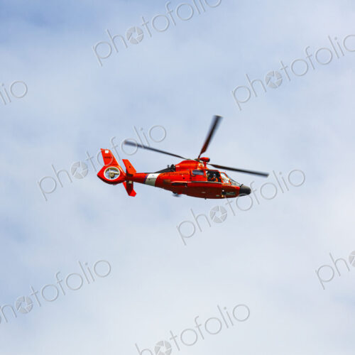 US Coast Guard helicopter hovering over the water in a demo of a rescue for a sea swimmer.