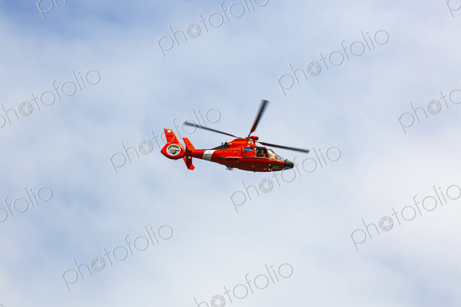 US Coast Guard helicopter hovering over the water in a demo of a rescue for a sea swimmer.