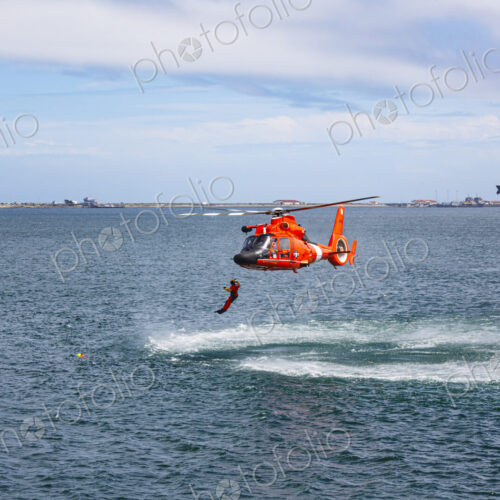 US Coast Guard helicopter hovering over the water in a demo of a rescue for a sea swimmer.