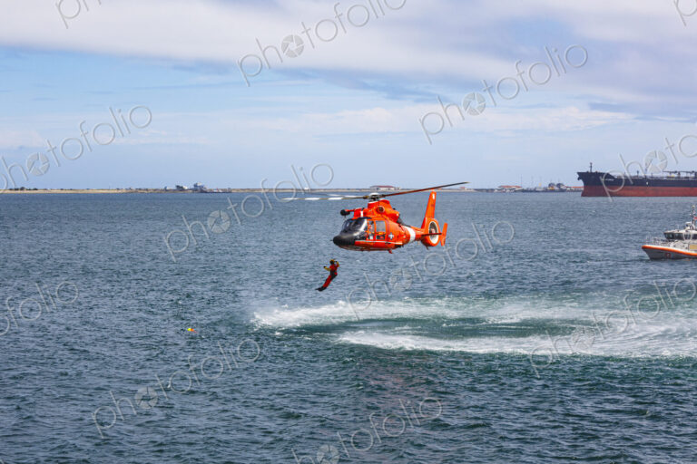 US Coast Guard helicopter hovering over the water in a demo of a rescue for a sea swimmer.