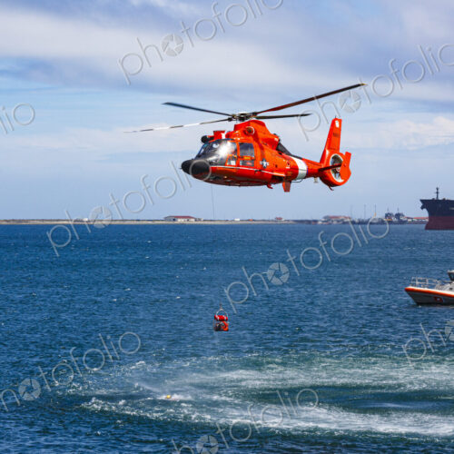 US Coast Guard helicopter hovering over the water in a demo of a rescue for a sea swimmer.