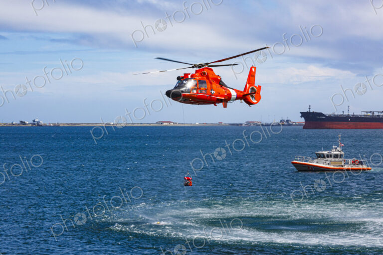 US Coast Guard helicopter hovering over the water in a demo of a rescue for a sea swimmer.