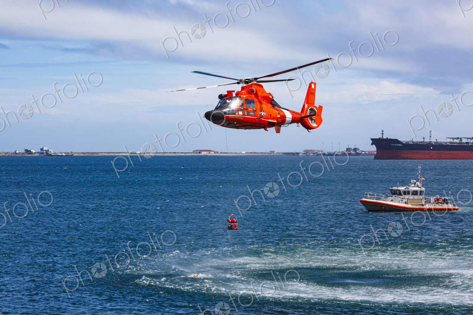 US Coast Guard helicopter hovering over the water in a demo of a rescue for a sea swimmer.