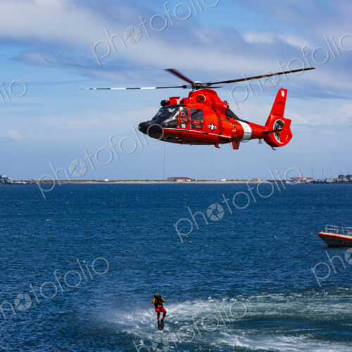 US Coast Guard helicopter hovering over the water in a demo of a rescue for a sea swimmer.