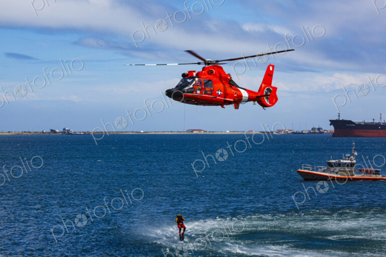 US Coast Guard helicopter hovering over the water in a demo of a rescue for a sea swimmer.