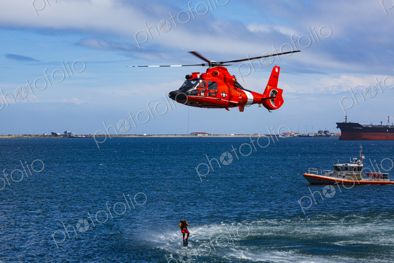 US Coast Guard helicopter hovering over the water in a demo of a rescue for a sea swimmer.