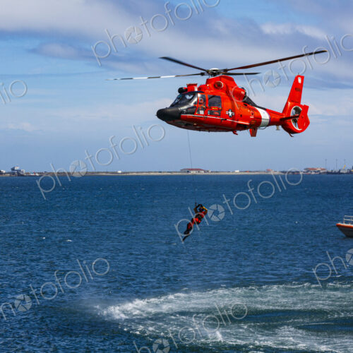 US Coast Guard helicopter hovering over the water in a demo of a rescue for a sea swimmer.