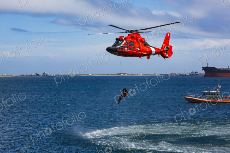 US Coast Guard helicopter hovering over the water in a demo of a rescue for a sea swimmer.