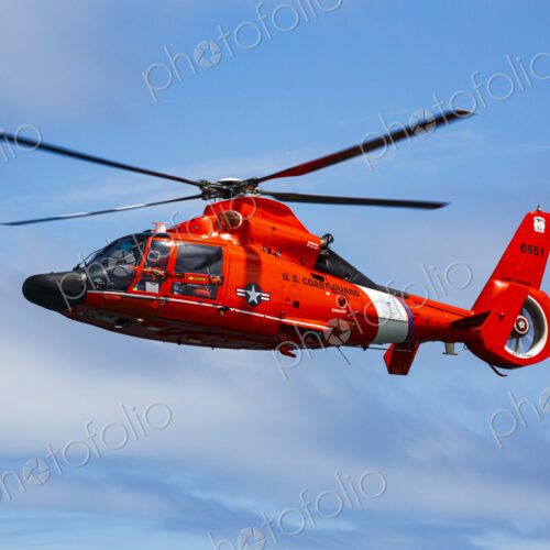 US Coast Guard helicopter hovering over the water in a demo of a rescue for a sea swimmer.
