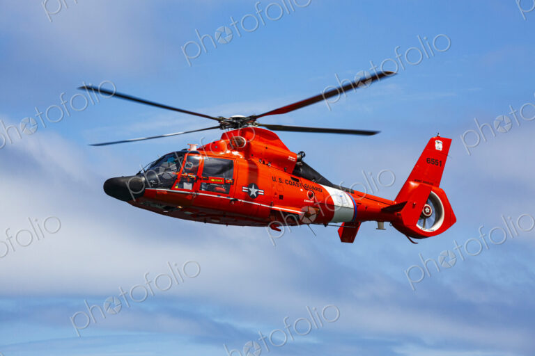 US Coast Guard helicopter hovering over the water in a demo of a rescue for a sea swimmer.