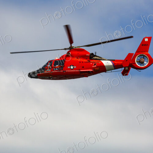 US Coast Guard helicopter hovering over the water in a demo of a rescue for a sea swimmer.