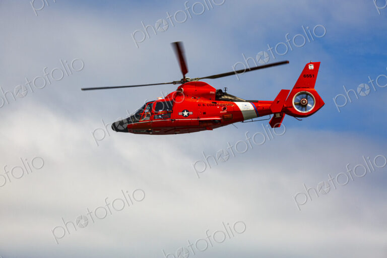 US Coast Guard helicopter hovering over the water in a demo of a rescue for a sea swimmer.