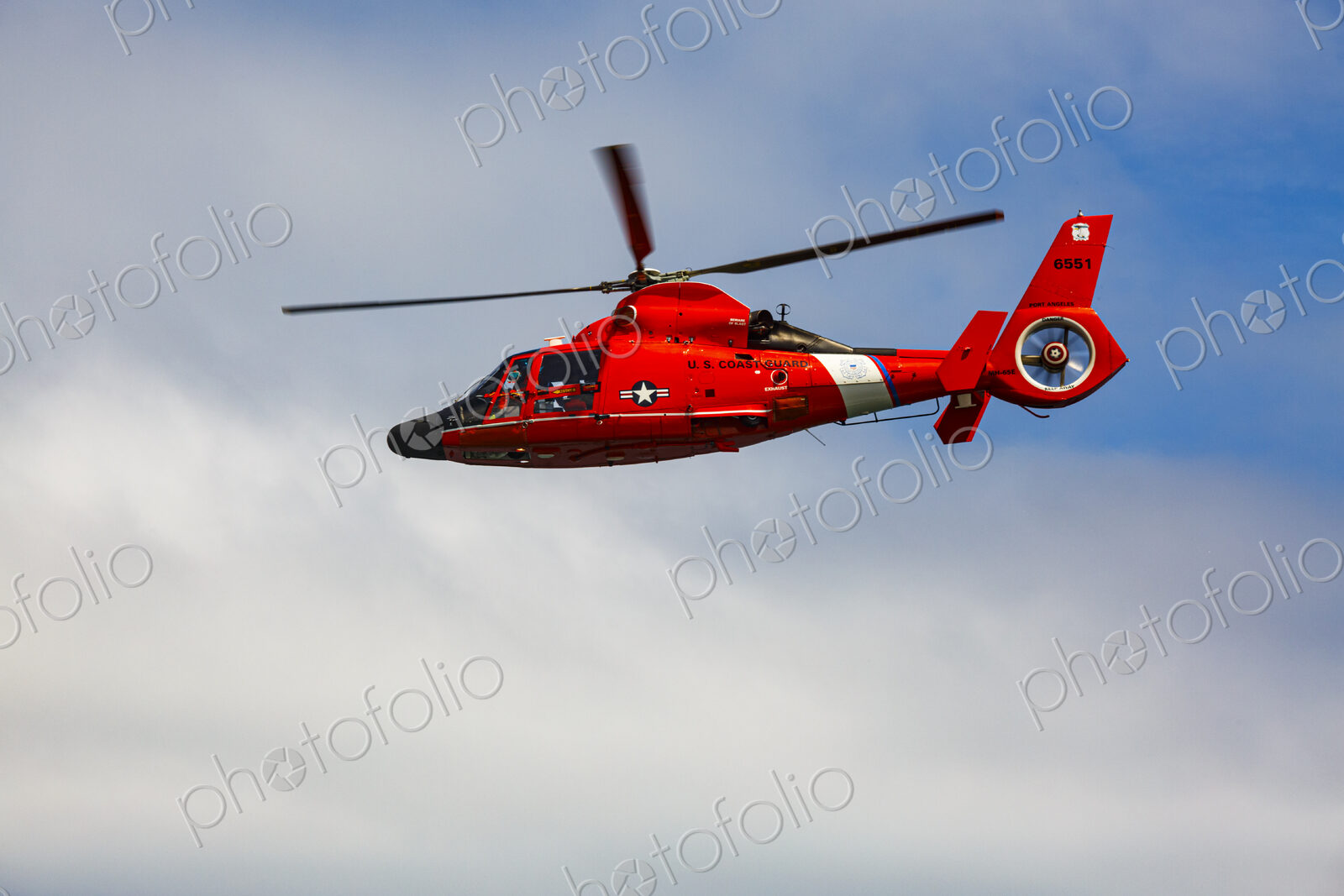 US Coast Guard helicopter hovering over the water in a demo of a rescue for a sea swimmer.