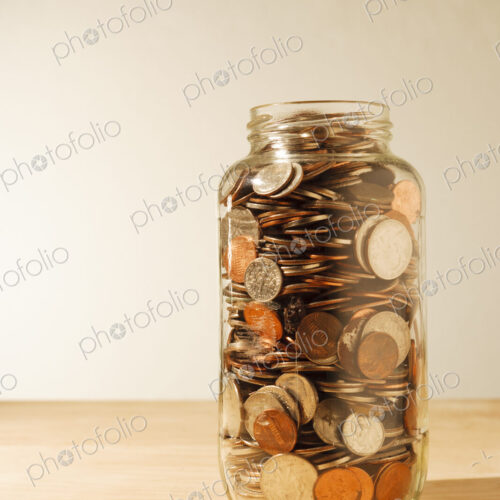 US coins collected in a glass jar, quarters, dollars, nickels and dimes.