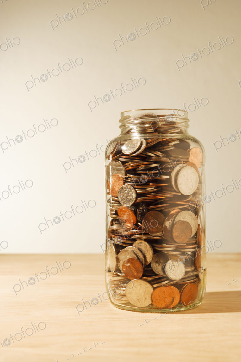 US coins collected in a glass jar, quarters, dollars, nickels and dimes.