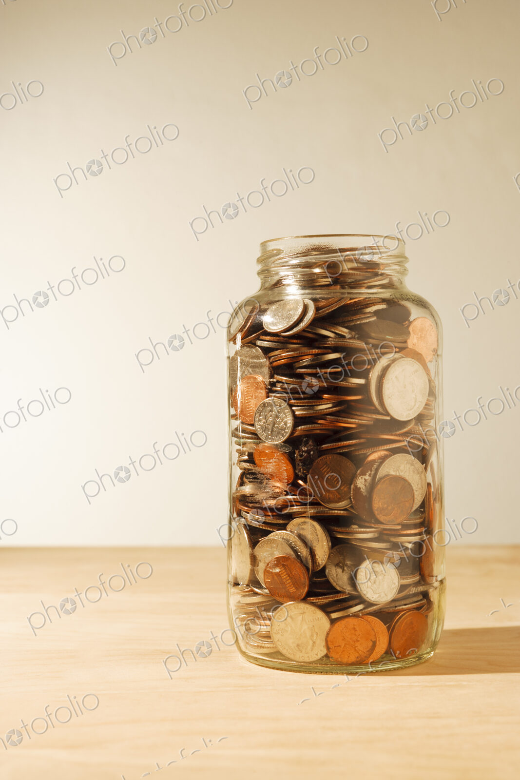 US coins collected in a glass jar, quarters, dollars, nickels and dimes.