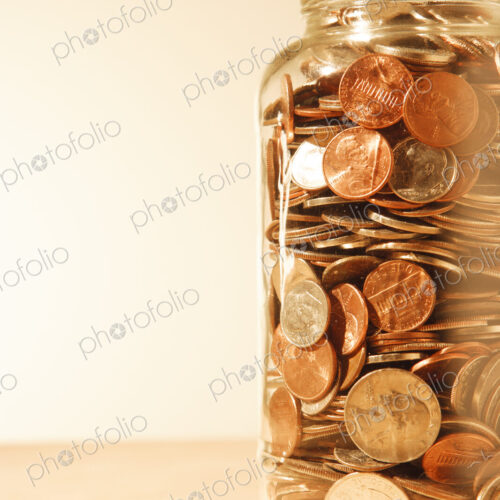 US coins collected in a glass jar, quarters, dollars, nickels and dimes.