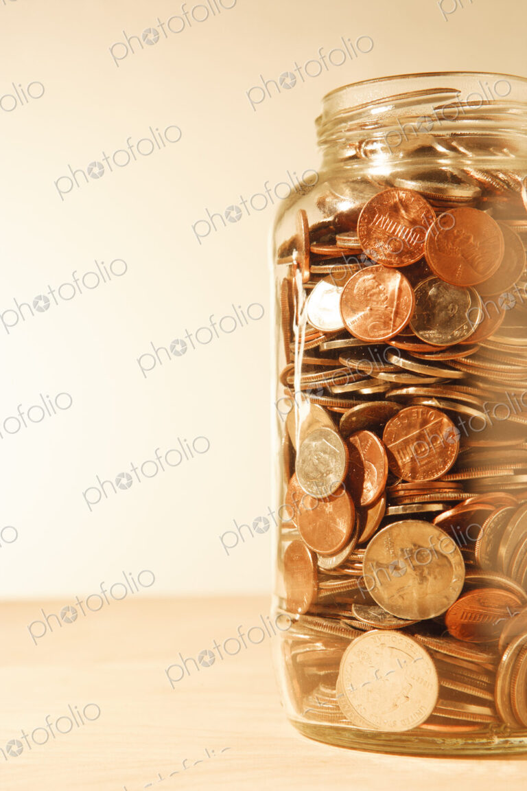 US coins collected in a glass jar, quarters, dollars, nickels and dimes.