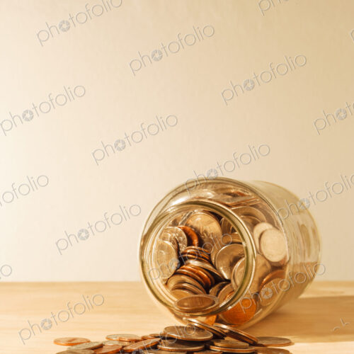 US coins collected in a glass jar, quarters, dollars, nickels and dimes.