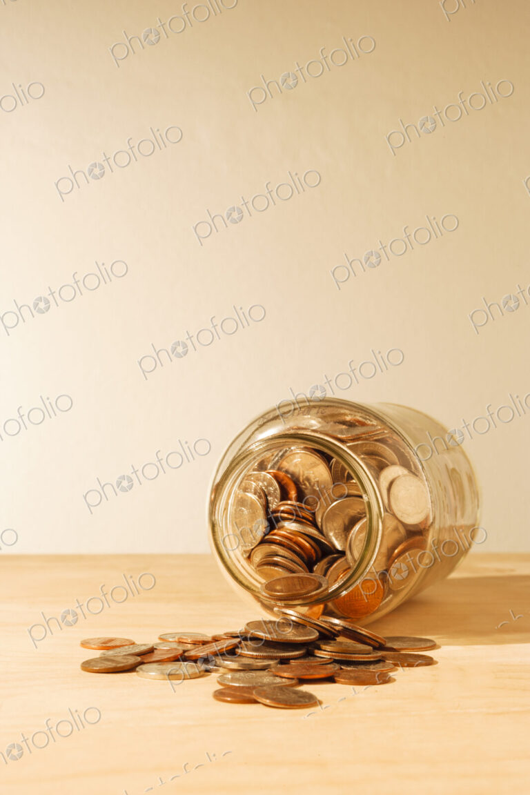 US coins collected in a glass jar, quarters, dollars, nickels and dimes.