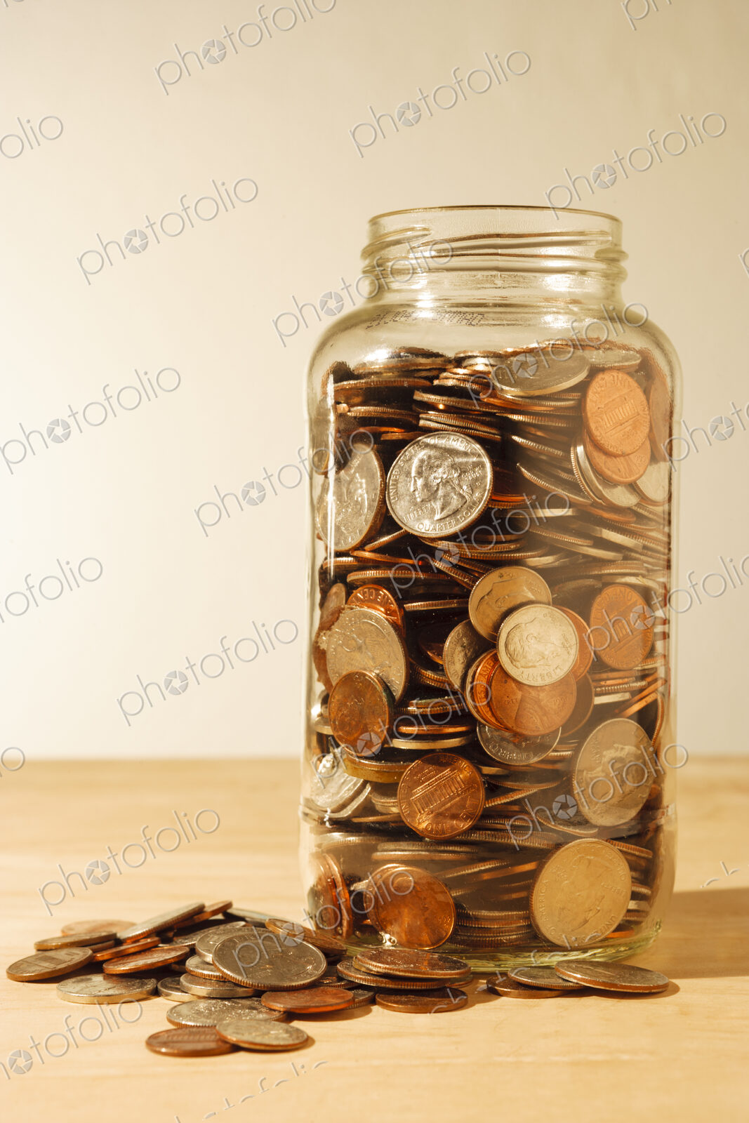 US coins collected in a glass jar, quarters, dollars, nickels and dimes.