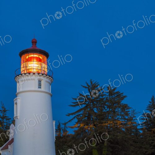 Umpqua Lighthouse illuminated at dusk, standing tall among coastal trees in Winchester… Umpqua Lighthouse illuminated at dusk, standing tall among coastal trees in Winchester…
