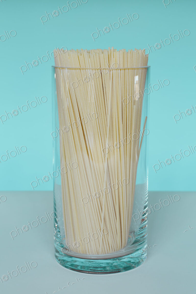 Uncooked organic pasta noodles in glass vase. Spaghetti noodles made of organic durum…