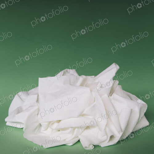 Unfurled, unwound toilet paper in a heap on a green background.