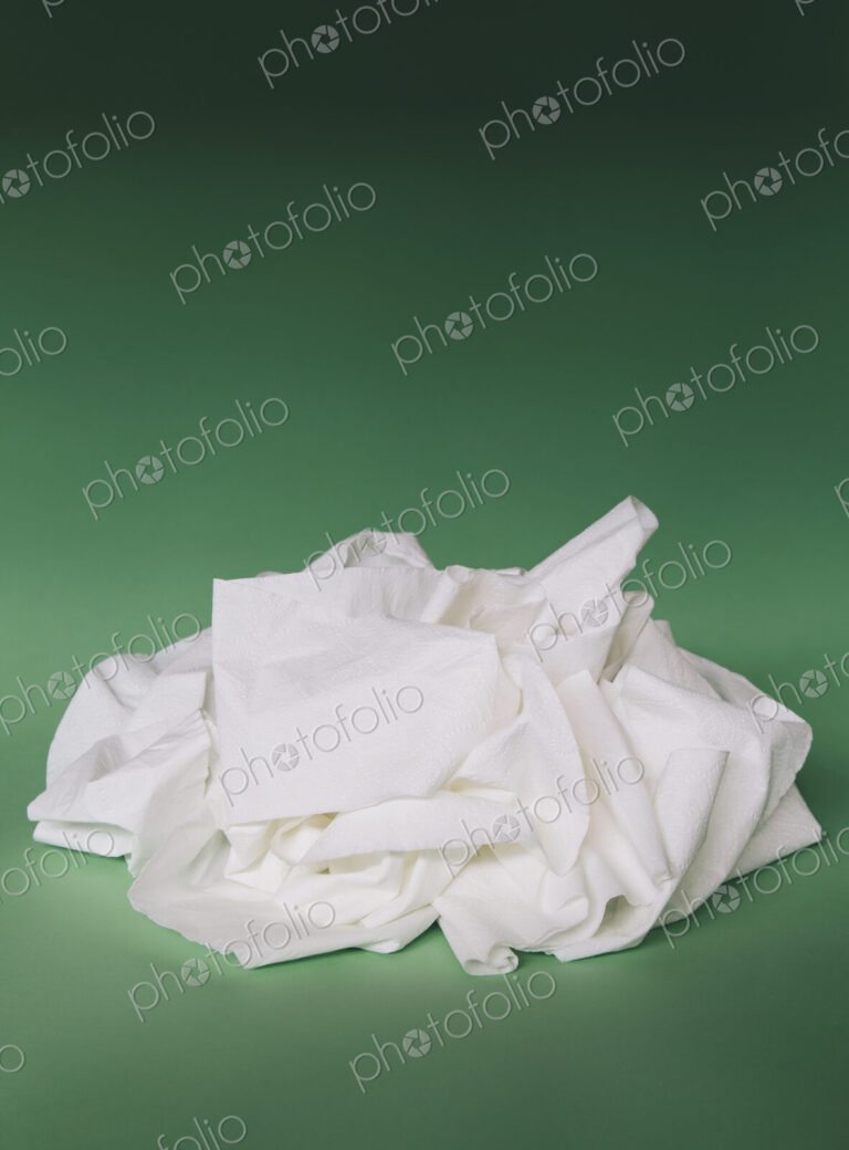 Unfurled, unwound toilet paper in a heap on a green background.