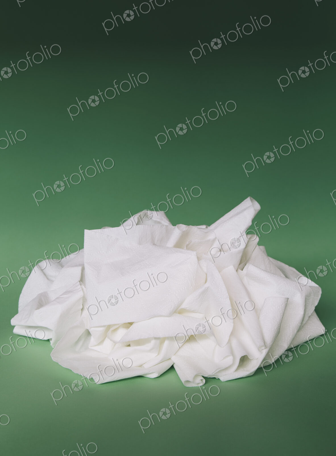 Unfurled, unwound toilet paper in a heap on a green background.
